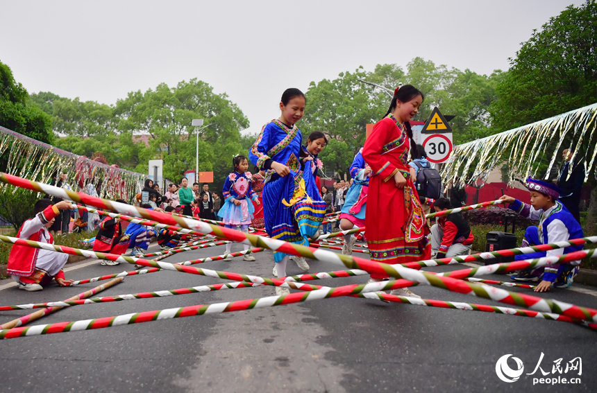 在洋林歸僑少數民族村，村裡的小朋友跳起竹竿舞迎接四海賓朋。 人民網記者 時雨攝