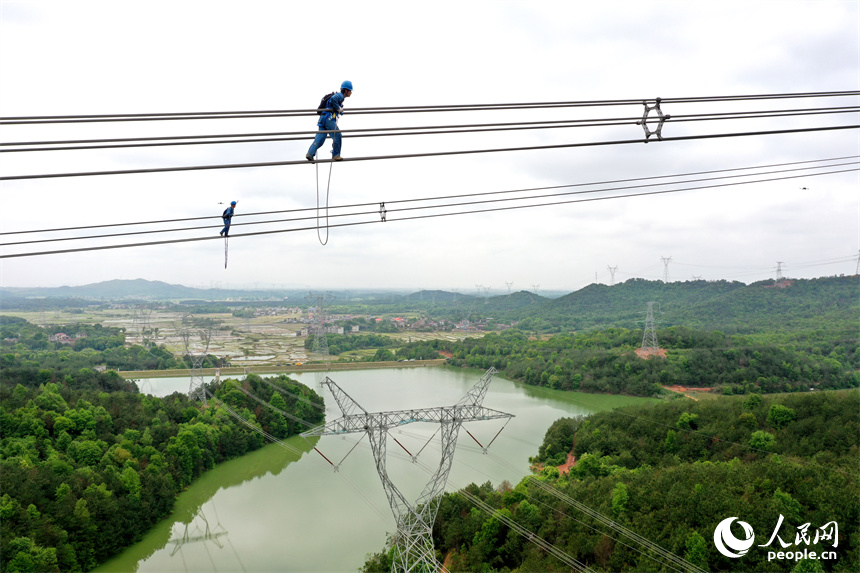 國網江西電力有限公司的檢修人員正在雅湖特高壓電網上走線進行年度檢修作業。 人民網記者 時雨攝