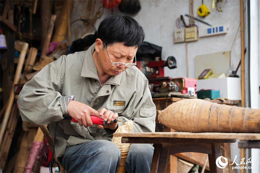 江西省级非遗项目根雕代表性传承人刘四喜在用电动工具对作品进行打磨。人民网 孔文进摄