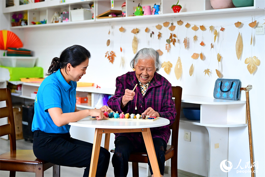 九江市湖口縣的一家養老公寓，工作人員陪伴老年人玩益智游戲。人民網 朱海鵬攝