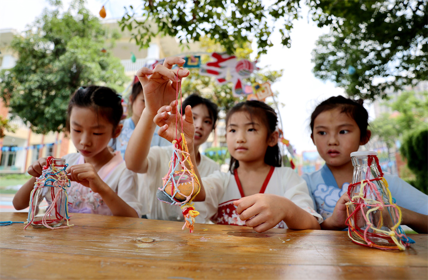 小朋友們展示自己編制的五彩繩。鄭飛華攝