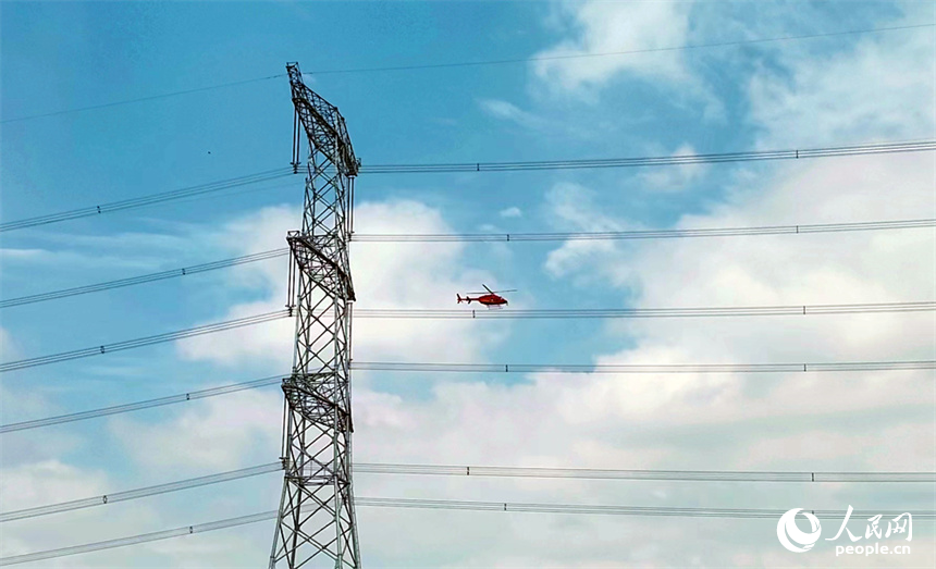 直升机穿梭在特高压电线旁开展特高压工程验收作业。人民网记者 时雨摄