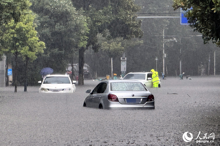 強降雨導致路面積水車輛被困，交警正與駕車人員溝通，協助脫困。人民網記者 時雨攝