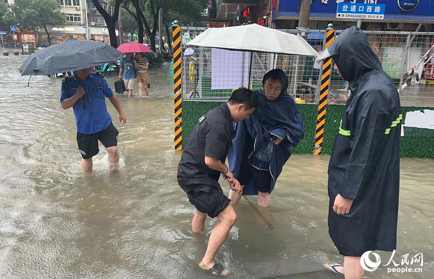 南昌丁公路樂盈廣場路段積水嚴重，丁公路街道綜合執法隊工作人員正在冒雨排水。人民網記者 時雨攝