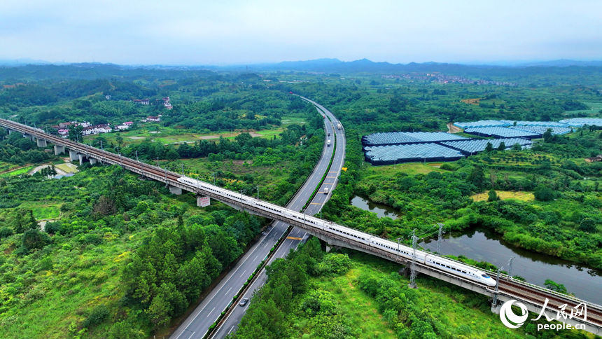 抚州市南丰县洽湾镇西坪村，昌福高铁列车、济广高速车辆穿境而过，沿线乡村田园、草木郁郁葱葱，美景如画。人民网 朱海鹏摄