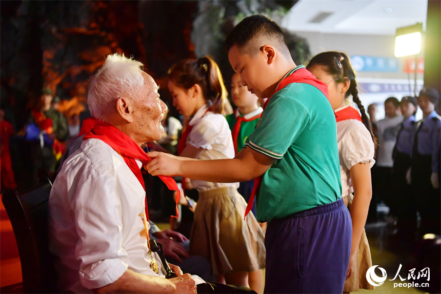 學生們為抗戰老兵代表戴紅領巾，表達敬意。人民網記者 時雨攝