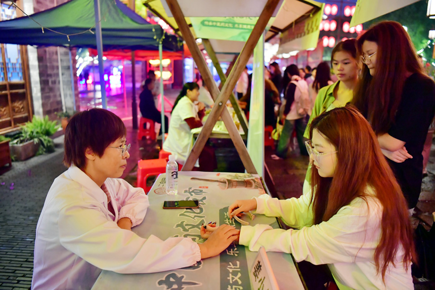 中医在夜市上为市民把脉问诊、答疑解惑。人民网记者 时雨摄