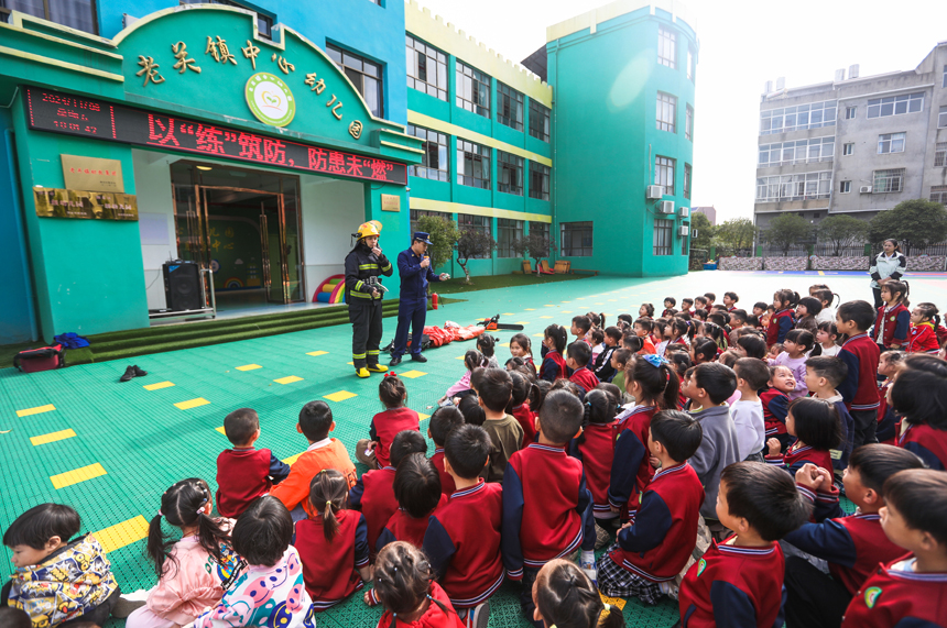 萍鄉市湘東區老關鎮中心幼兒園，消防員正指導小朋友們體驗消防器材使用方法。彭亮攝