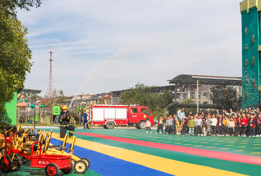 萍鄉市湘東區老關鎮中心幼兒園，消防員正指導小朋友們體驗消防器材使用方法。彭亮攝