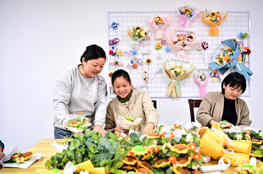 吉安市廬陵新區余家河社區就業之家，許多社區居民在“微工坊”裡編織手工毛絨花。人民網 朱海鵬攝