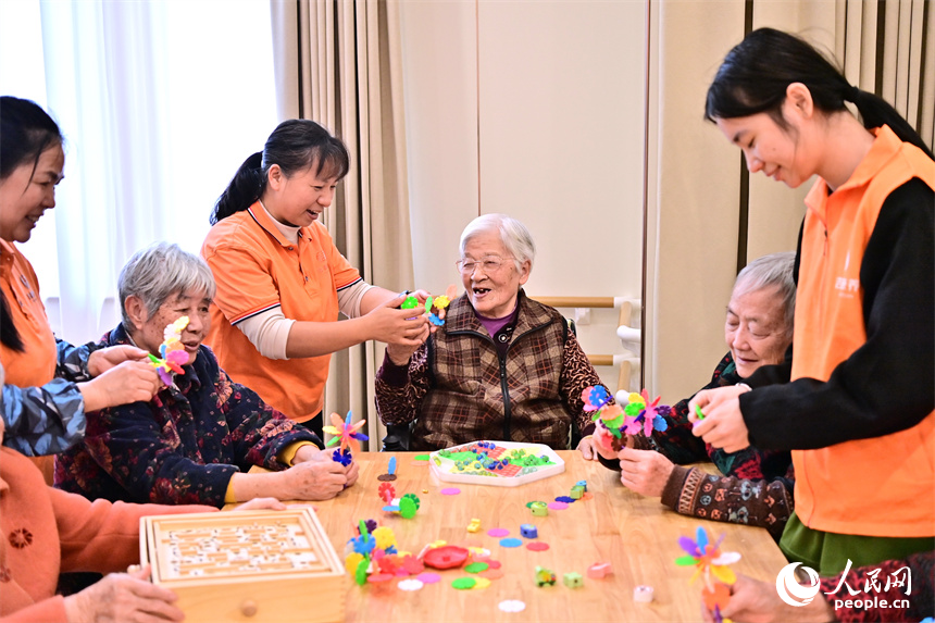 吉安市廬陵新區鳳凰社區養老中心，護工在陪伴老年人玩益智游戲。人民網 朱海鵬攝