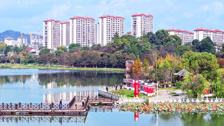 宜豐縣新昌湖省級濕地公園，色彩斑斕的林木與清澈湖水、九曲浮橋、林立樓群相映成景。何賤來攝