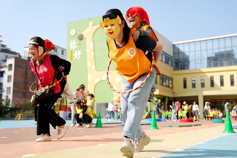 上高縣第三幼兒園的孩子們和家長一起合作完成“豬八戒背媳婦”游戲。陳旗海攝