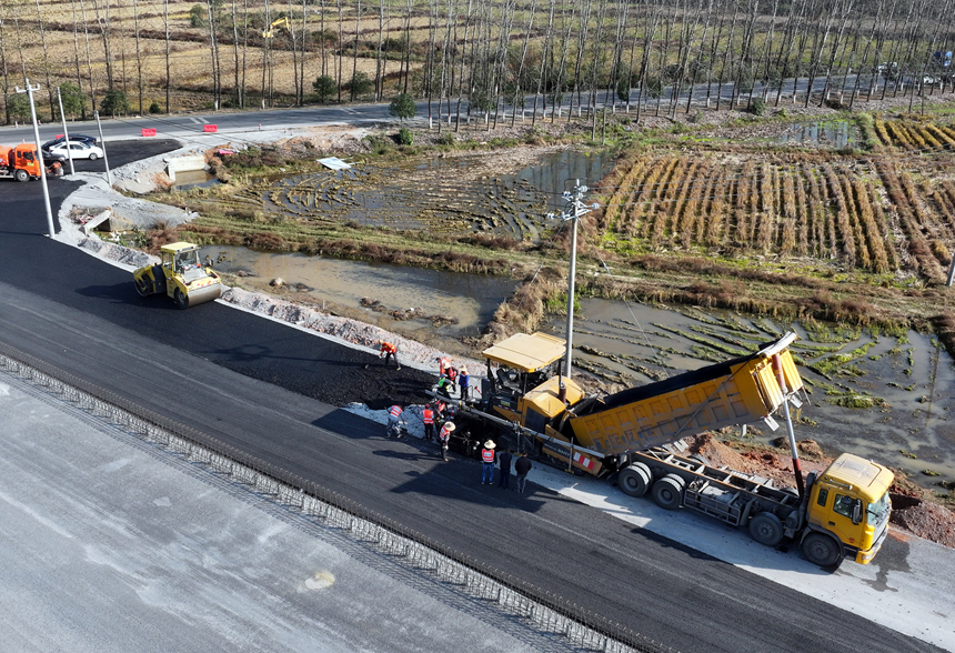 宜豐縣新昌鎮荷舍村路段至該縣工業園區等地近3.2公路的新建一級公路施工現場，筑路工人正忙著鋪瀝青。何賤來攝