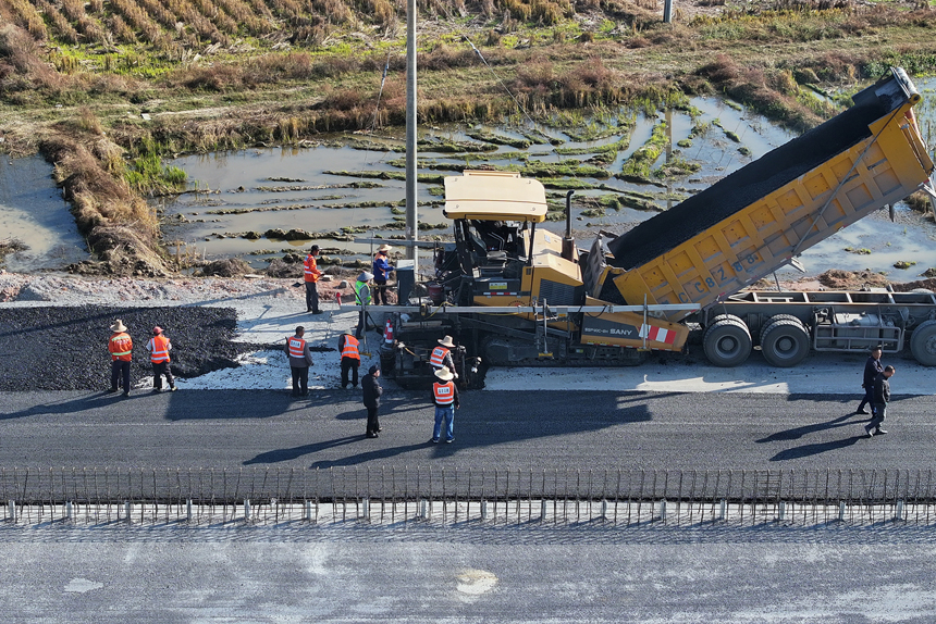 宜豐縣新昌鎮荷舍村路段至該縣工業園區等地近3.2公路的新建一級公路施工現場，筑路工人正忙著鋪瀝青。何賤來攝