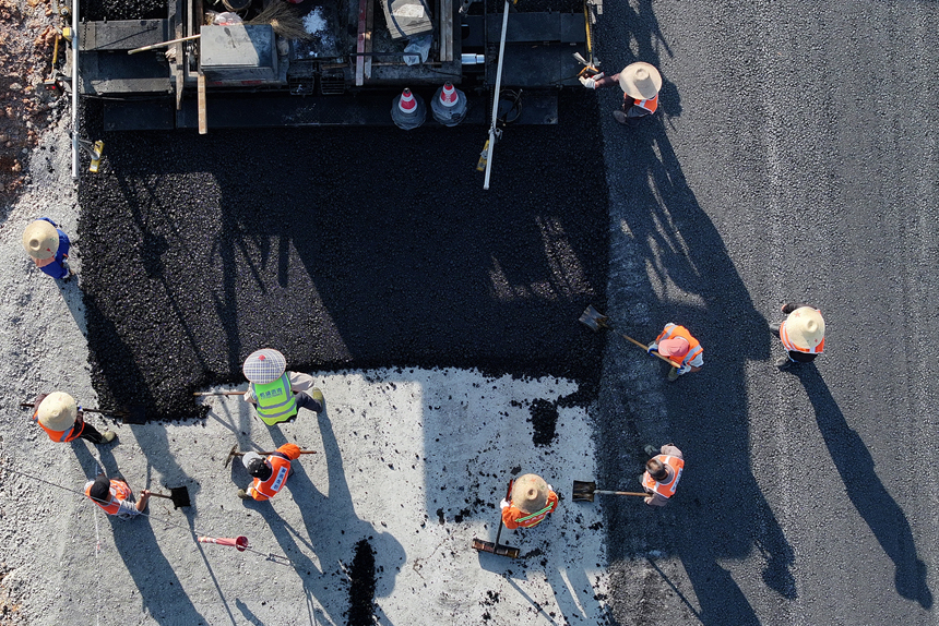 宜豐縣新昌鎮荷舍村路段至該縣工業園區等地近3.2公路的新建一級公路施工現場，筑路工人正忙著鋪瀝青。何賤來攝