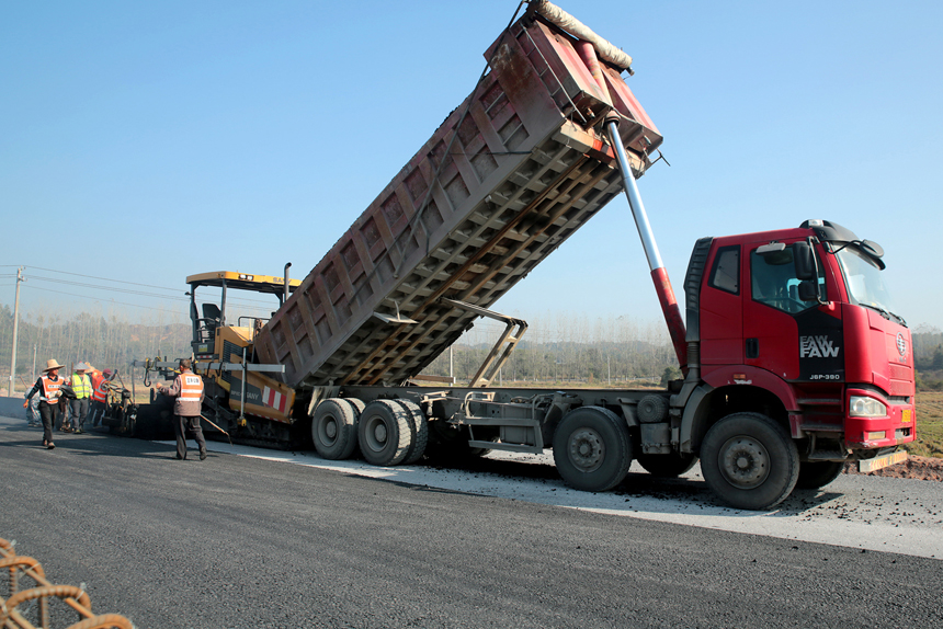 宜豐縣新昌鎮荷舍村路段至該縣工業園區等地近3.2公路的新建一級公路施工現場，筑路工人正忙著鋪瀝青。何賤來攝