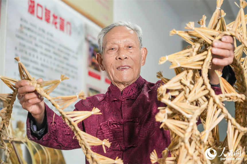 国家级非遗项目湖口草龙（草编）代表性传承人喻芳泽在展示龙鳞部件。人民网 孔文进摄