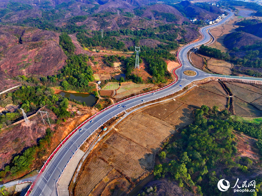 上饒市弋陽縣圭峰鎮，車輛在蜿蜒的公路上穿行，與沿線丹霞地貌山丘相映成景。人民網 朱海鵬攝