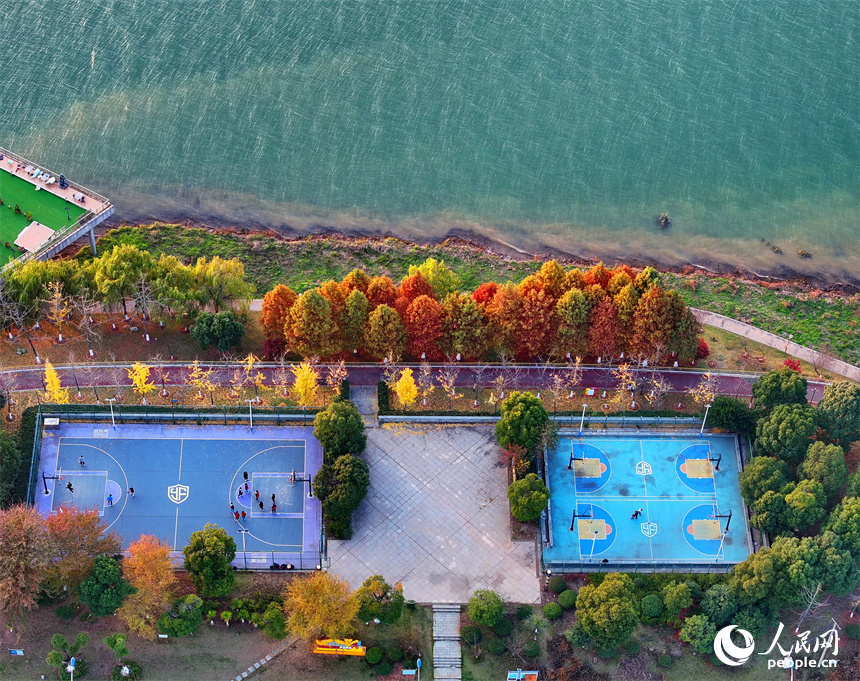 吉安市吉水縣贛江沿岸的一處“口袋公園”，許多市民在打籃球，色彩斑斕的樹木與籃球場、健身步道、碧綠江水相映襯。人民網 朱海鵬攝