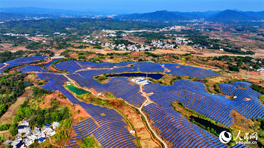 贛州市信豐縣正平鎮的一處農光互補光伏發電基地，太陽能光伏板與青山綠樹、村庄田園相映襯。人民網 朱海鵬攝