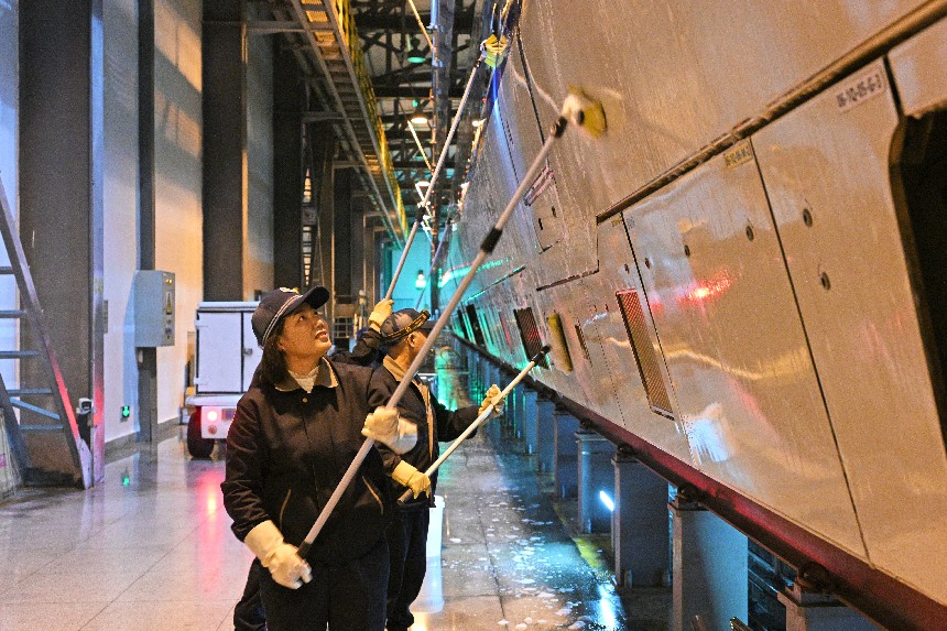 动车组洗车作业人员正在仔细清洗车侧裙板。董毅摄