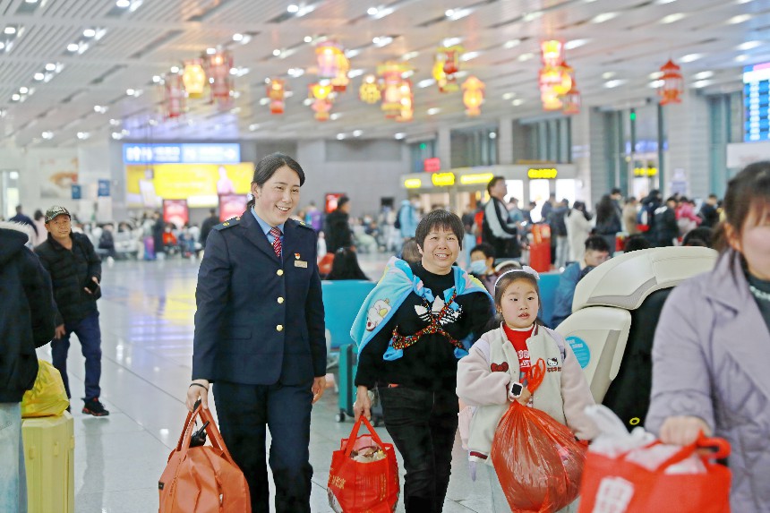 泉州站客運員羅穎為老人旅客提拿行李，並將老人及隨行的小朋友引導到候車區域。陳明攝