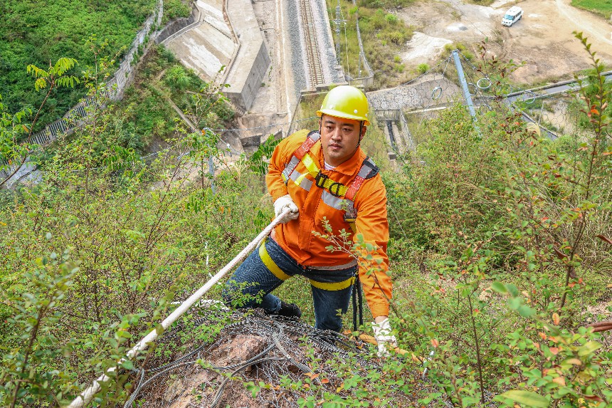 隊長馬國慶頭戴安全帽，在安全繩的幫助下，在幾乎垂直的山體上攀爬。李舜攝