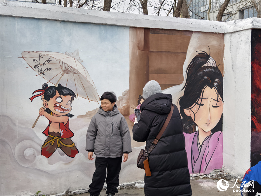 小朋友在哪吒主题彩绘墙前拍照留影。人民网记者 时雨摄