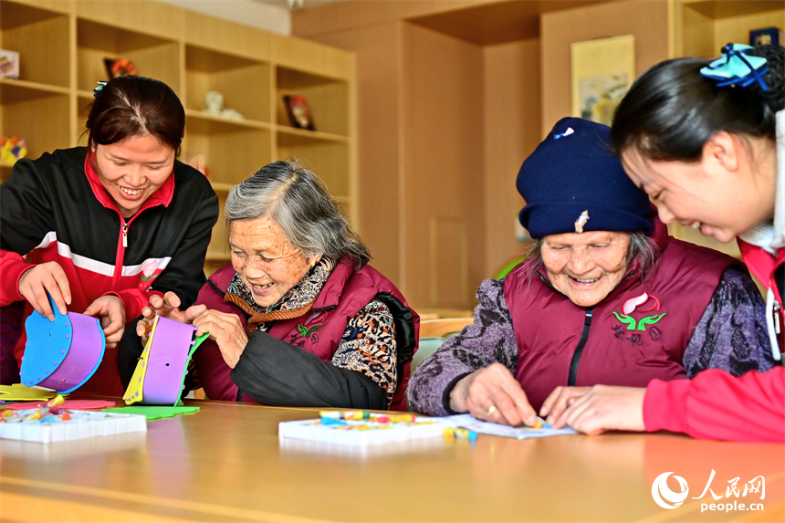 贛州市南康區蟠桃園老年公寓，護工在陪伴老人制作手工擺件。人民網 朱海鵬攝