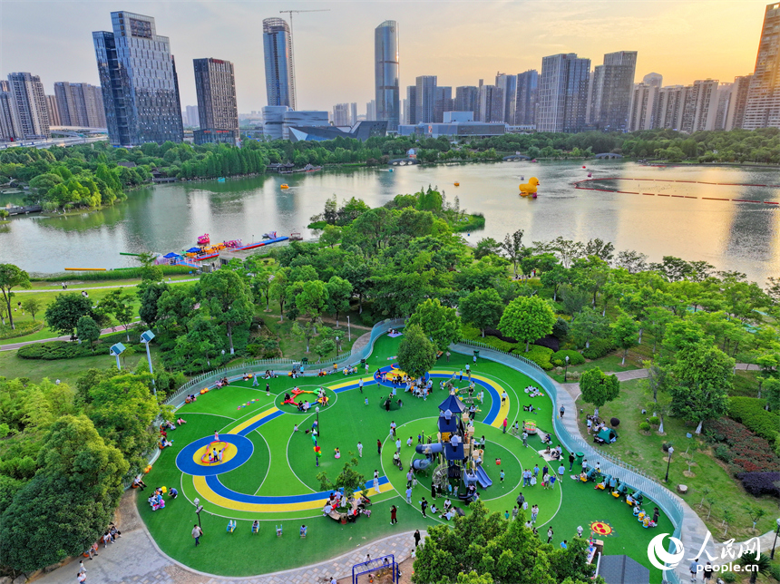 贛州市中心城區的一處公園裡，家長帶著孩子在兒童游樂園內游玩，樂享親子時光。人民網 朱海鵬攝