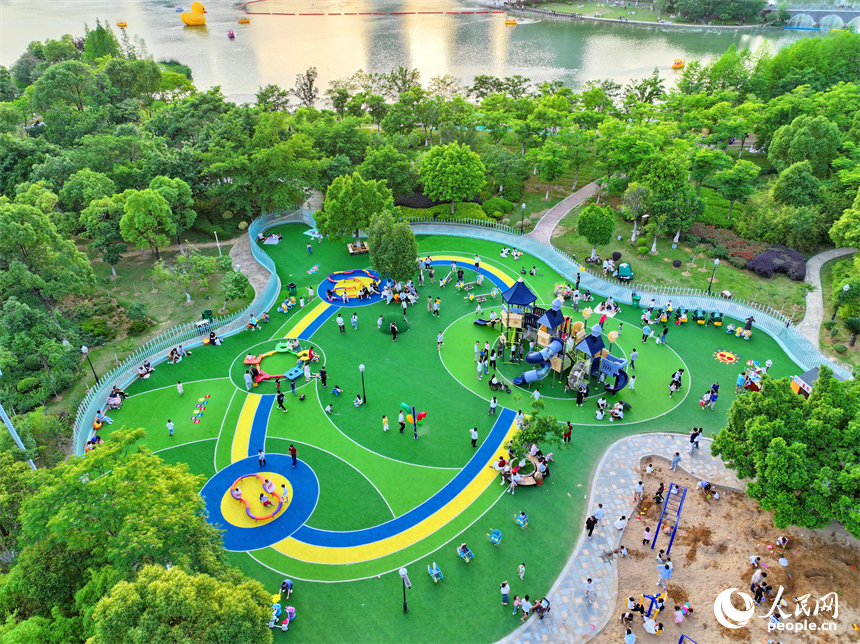 贛州市中心城區的一處公園裡，家長帶著孩子在兒童游樂園內游玩，樂享親子時光。人民網 朱海鵬攝
