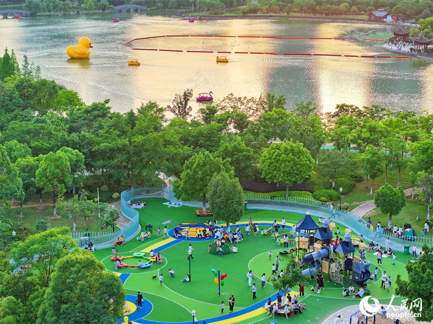 贛州市中心城區的一處公園裡，家長帶著孩子在兒童游樂園內游玩，樂享親子時光。人民網 朱海鵬攝