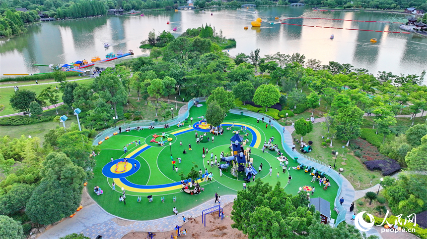 贛州市中心城區的一處公園裡，家長帶著孩子在兒童游樂園內游玩，樂享親子時光。人民網 朱海鵬攝