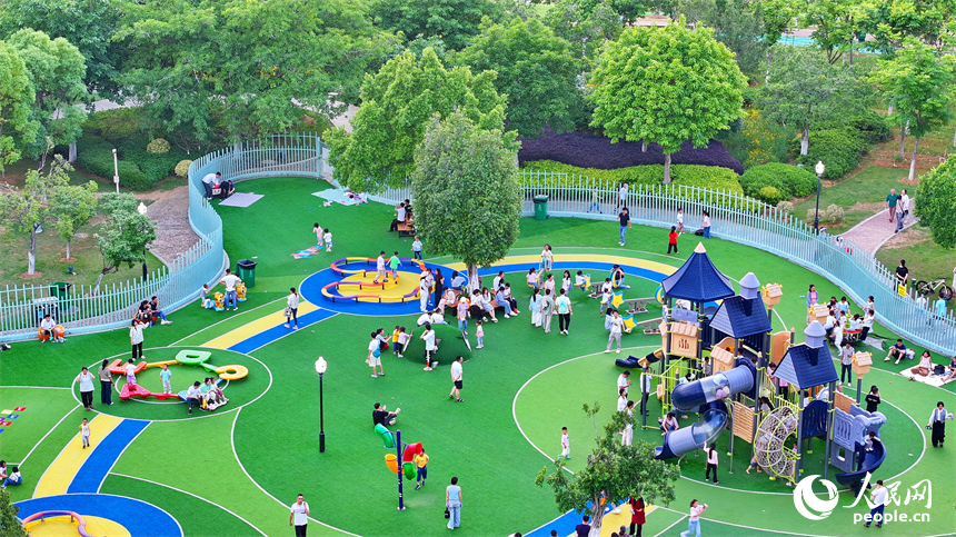 贛州市中心城區的一處公園裡，家長帶著孩子在兒童游樂園內游玩，樂享親子時光。人民網 朱海鵬攝