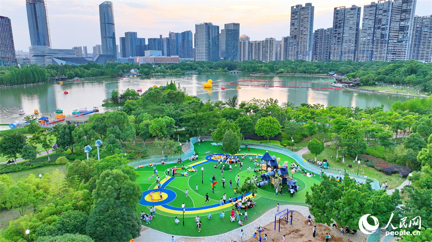 贛州市中心城區的一處公園裡，家長帶著孩子在兒童游樂園內游玩，樂享親子時光。人民網 朱海鵬攝