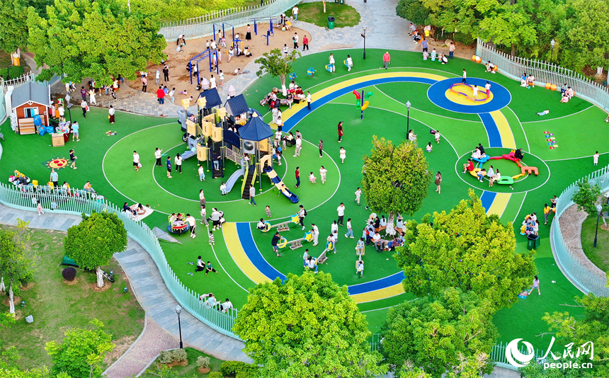 贛州市中心城區的一處公園裡，家長帶著孩子在兒童游樂園內游玩，樂享親子時光。人民網 朱海鵬攝