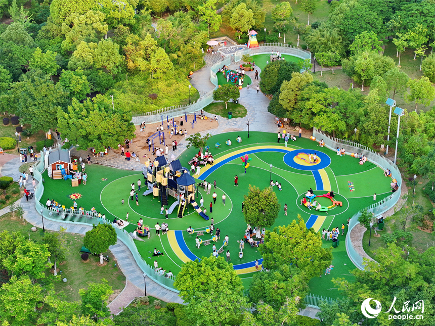 贛州市中心城區的一處公園裡，家長帶著孩子在兒童游樂園內游玩，樂享親子時光。人民網 朱海鵬攝