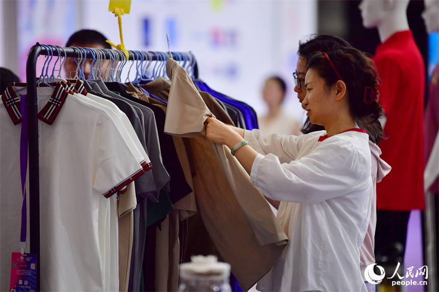 2025中國(南昌)國際服裝服飾博覽會在紅谷灘區舉行。圖為採購商正在挑選服飾產品。人民網記者 時雨攝