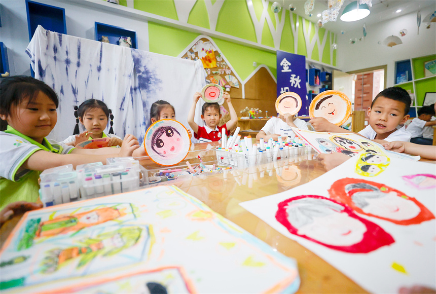 孩子们在美术课堂上描绘并展示自己创作的“笑脸”作品。郑飞华摄