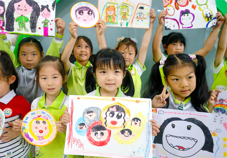 孩子們在美術課堂上描繪並展示自己創作的“笑臉”作品。鄭飛華攝
