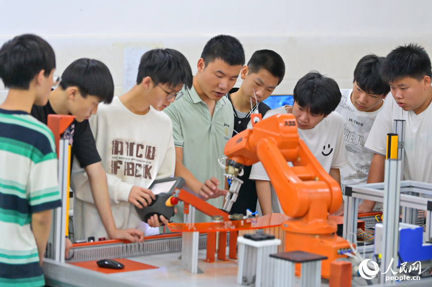 瑞金市瑞金中等專業學校工業機器人實訓基地，老師在指導學生在操作智能機械臂。人民網 朱海鵬攝