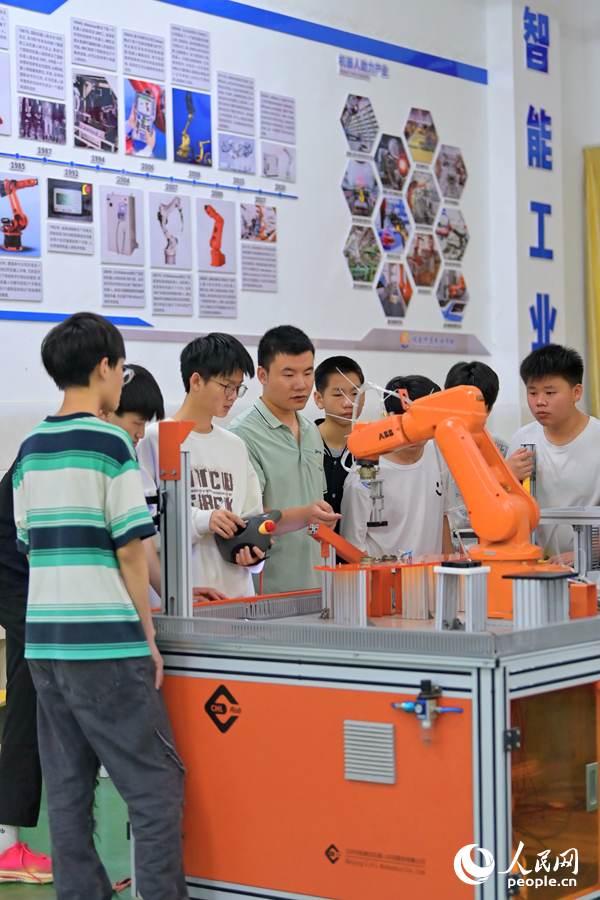 瑞金市瑞金中等专业学校工业机器人实训基地，老师在指导学生在操作智能机械臂。人民网 朱海鹏摄