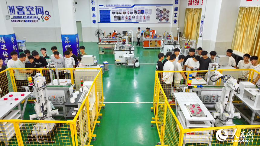 瑞金市瑞金中等专业学校工业机器人实训基地，老师在指导学生在操作智能机械臂。人民网 朱海鹏摄
