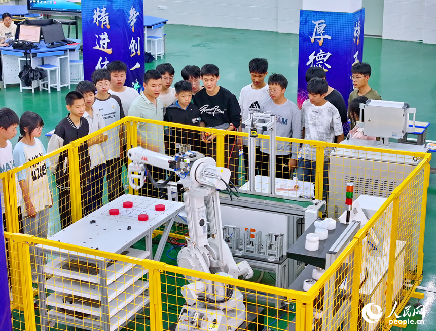 瑞金市瑞金中等专业学校工业机器人实训基地，老师在指导学生在操作智能机械臂。人民网 朱海鹏摄