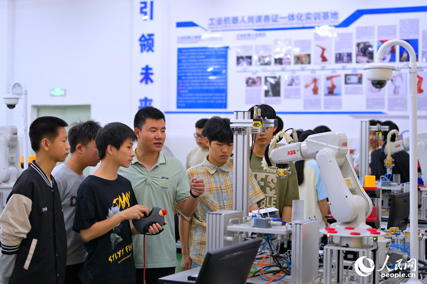 瑞金市瑞金中等专业学校工业机器人实训基地，老师在指导学生在操作智能机械臂。人民网 朱海鹏摄
