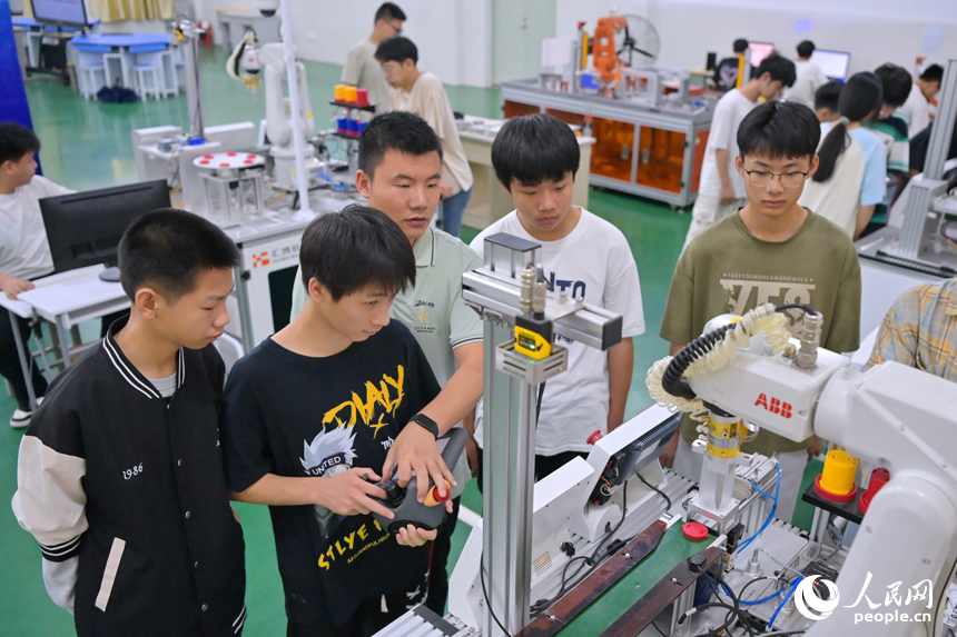 瑞金市瑞金中等专业学校工业机器人实训基地，老师在指导学生在操作智能机械臂。人民网 朱海鹏摄