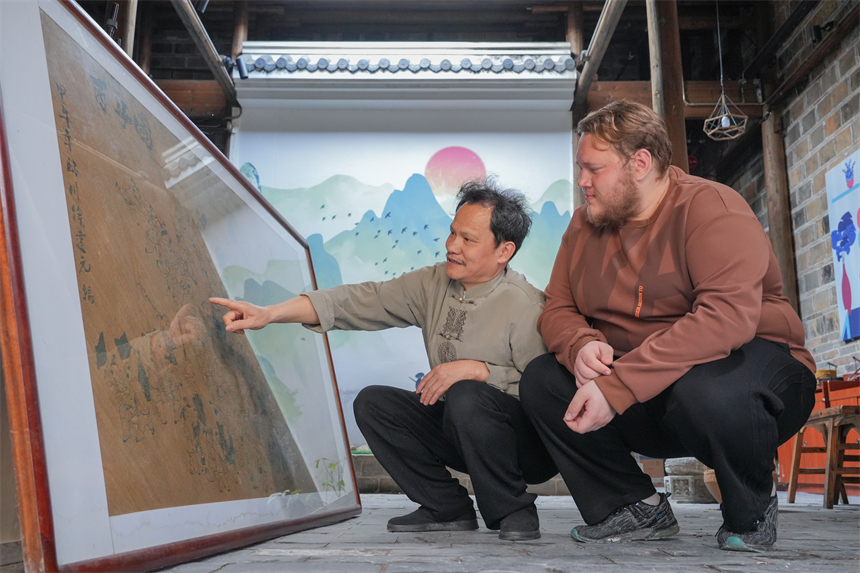 徐建元在向留學生白熙華介紹篾編作品《百子圖》。人民網 孔文進攝