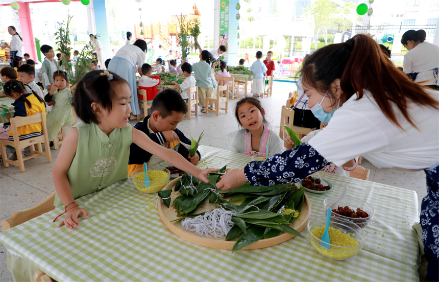 2025年5月30日，在江西省贛州市全南縣第四幼兒園，老師指導孩子裹粽子。