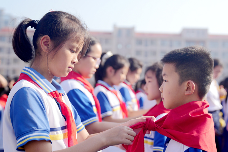 中国少年先锋队老队员为新入队的学生佩戴红领巾。陈旗海摄